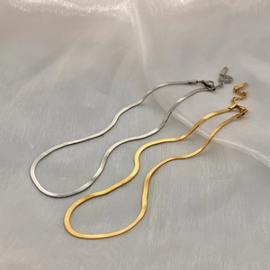 Sleek gold and silver snake chain necklaces with lobster clasp on elegant white fabric