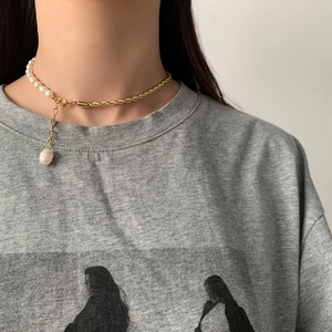 Gros plan sur collier en perles d'eau douce baroques et chaîne dorée torsadée