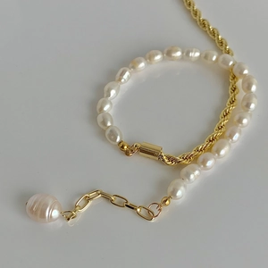 Gros plan d'un bracelet en perles d'eau douce baroques avec chaîne dorée et breloque perle
