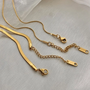 Macro detail of gold-plated stainless steel herringbone chain with secure lobster clasp