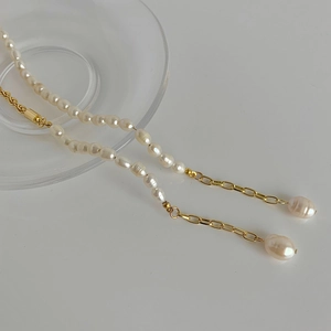 Détail du collier en perles d'eau douce baroques avec chaîne dorée et pendentifs