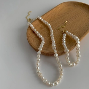 Gros plan sur l'ensemble collier et bracelet en perles baroques avec chaîne dorée ajustable