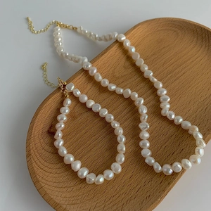 Ensemble collier et bracelet en perles baroques avec fermoir doré sur un plateau en bois