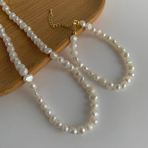 Détail d'un collier de perles d'eau douce baroques avec fermoir mousqueton doré et extension