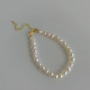 Détail d'un bracelet en perles d'eau douce naturelles avec fermoir mousqueton doré chic