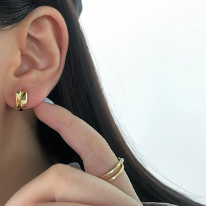 Detail of gold-plated twisted hoop earrings and double-layered faux pearl ring