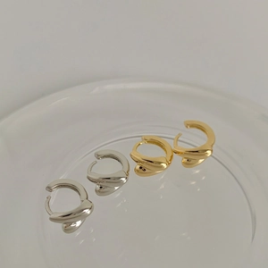 Detailed view of twisted huggie hoop earrings in polished gold and silver finishes