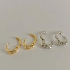 Detail of gold and silver twisted C-shaped earrings set with polished finish