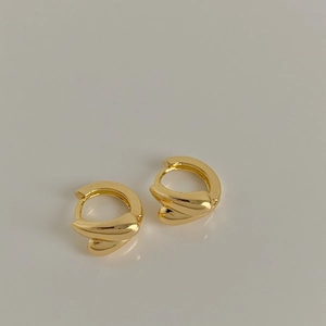 Macro view of gold-plated waterdrop twist earrings with a refined metallic texture