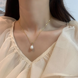 Elegant gold chain necklace with a white baroque freshwater pearl on a female model