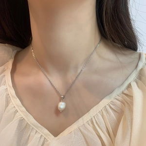 Close-up of minimalist freshwater pearl necklace on model with golden chain detail