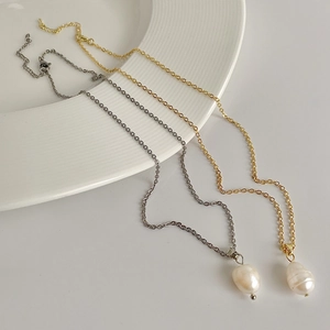 Elegant gold and silver baroque freshwater pearl necklaces on a white textured ceramic dish