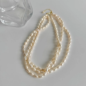 Three-layer baroque pearl necklace with gold-plated clasp on a white background