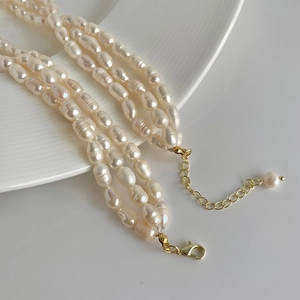 Detailed macro shot of three-layer Baroque freshwater pearl necklace with gold clasp
