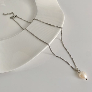 Baroque freshwater pearl pendant on a minimalist gold-plated chain over a ceramic plate