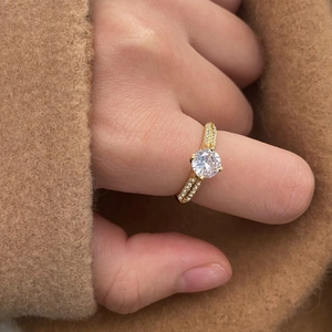 Elegant gold-plated solitaire ring with shimmering zircon pavé worn by a model