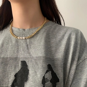 Detail of chunky gold chain necklace with three round freshwater pearls on neck