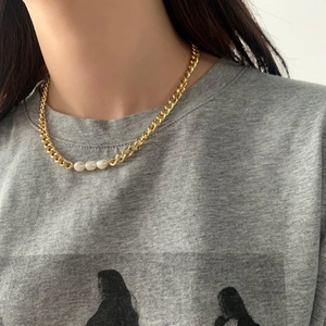 Detailed view of a gold chunky chain necklace with three white freshwater pearls on a model