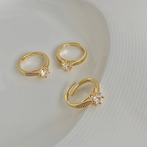 Detail of adjustable gold rings featuring central zircon and pavé set small diamonds