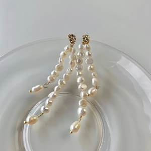 Baroque freshwater pearl tassel earrings with gold-toned metal posts in a glass dish