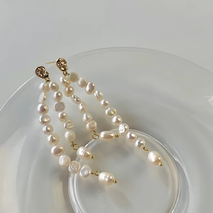 Macro detail of multi-layered Baroque pearl drop earrings with hammered gold texture finish
