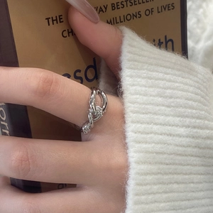 Close-up of a silver-plated twisted knot ring on a finger with a cozy sweater background