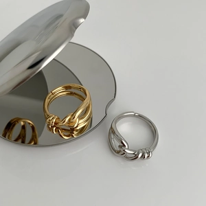 Detail of minimalist knotted geometric open rings in polished gold and silver finishes