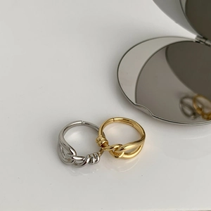 Detail of gold and silver knotted geometric rings reflecting in a metal mirror