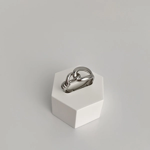 Detail shot of silver chain-link ring displayed on a white hexagonal geometric stand