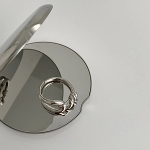 Detail of a minimalist silver knot ring with polished double bands on a reflective mirror