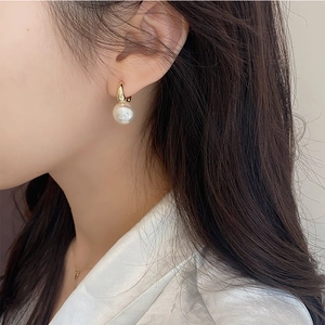Elegant gold U-shaped pearl earrings on a model, showcasing minimalist geometric style