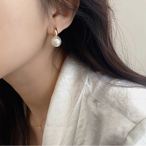 Elegant gold plated hoop earrings with large white round pearls shown on model