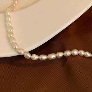 Detailed view of natural baroque pearls on elegant white ceramic and dark velvet fabric