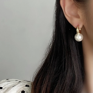 Close-up of minimalist gold pearl hoop earrings worn by a model in a side profile view