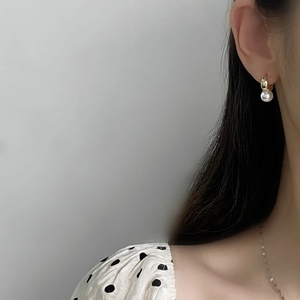 Detail of elegant gold teardrop earrings with a lustrous round white pearl on a model