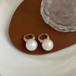 Detailed view of elegant gold pearl hoop earrings on a vintage brown leather display