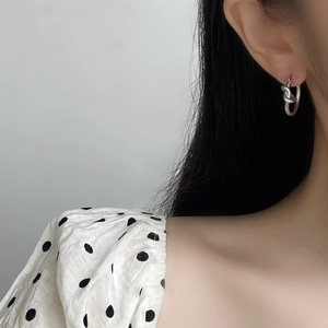 Boucle d'oreille noeud en argent minimaliste portée par un mannequin en gros plan