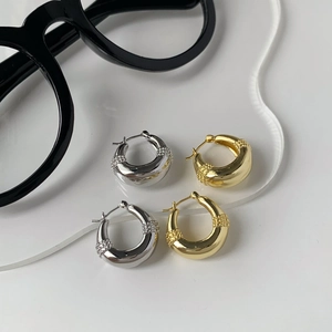Detailed view of gold and silver chunky teardrop hoop earrings with granulated texture