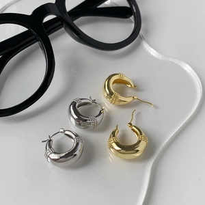 Detailed macro view of gold and silver chunky teardrop hoop earrings with bead textures