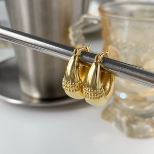 Macro shot of gold teardrop earrings with detailed beaded texture and high metal luster