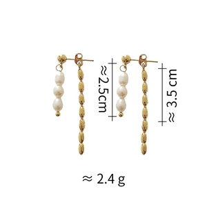 Detail view of asymmetric pearl and gold tassel earrings with length and weight markers