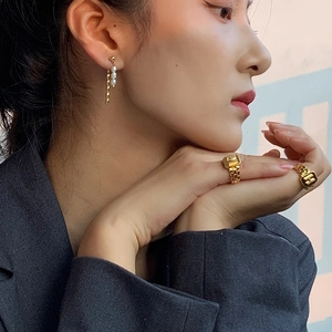Close-up of elegant gold tassel pearl earrings and classic H logo ring on a model