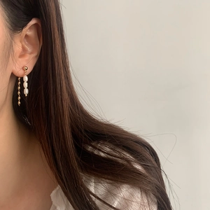 Detail of elegant gold fringe tassel earrings with pearls shown on a female model