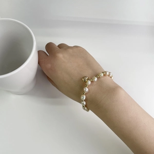 Elegant baroque freshwater pearl bracelet with a gold heart pendant on woman's wrist