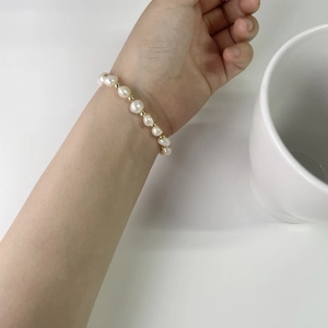 Close-up of a freshwater pearl bracelet with gold bead accents on a woman's wrist