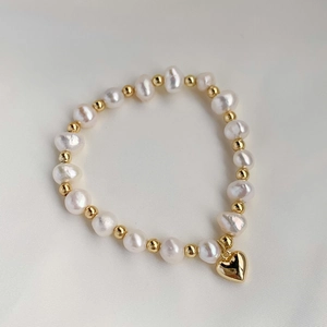 Detailed close-up of Baroque freshwater pearls and gold heart charm on elegant bracelet