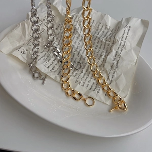 Detailaufnahme der Gold- und Silberketten mit Knebelverschluss auf Vintage-Papier