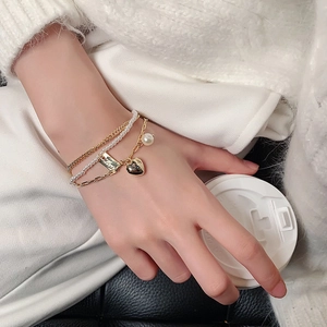 Elegant multi-layer gold heart bracelet with pearls on a model holding a coffee cup