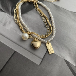 Detail of double-layer gold-plated bracelet with pearl accents and heart charm