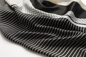 Macro view of geometric plaid silk scarf with elegant black and white stripe patterns